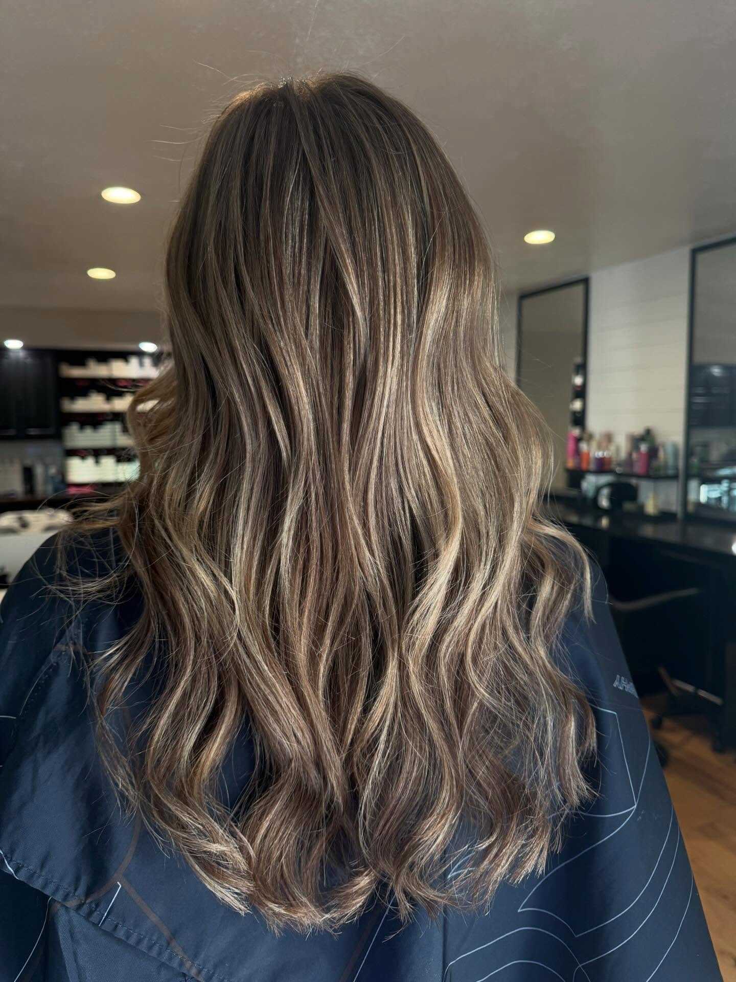 Long wavy hair with highlights in a salon setting.