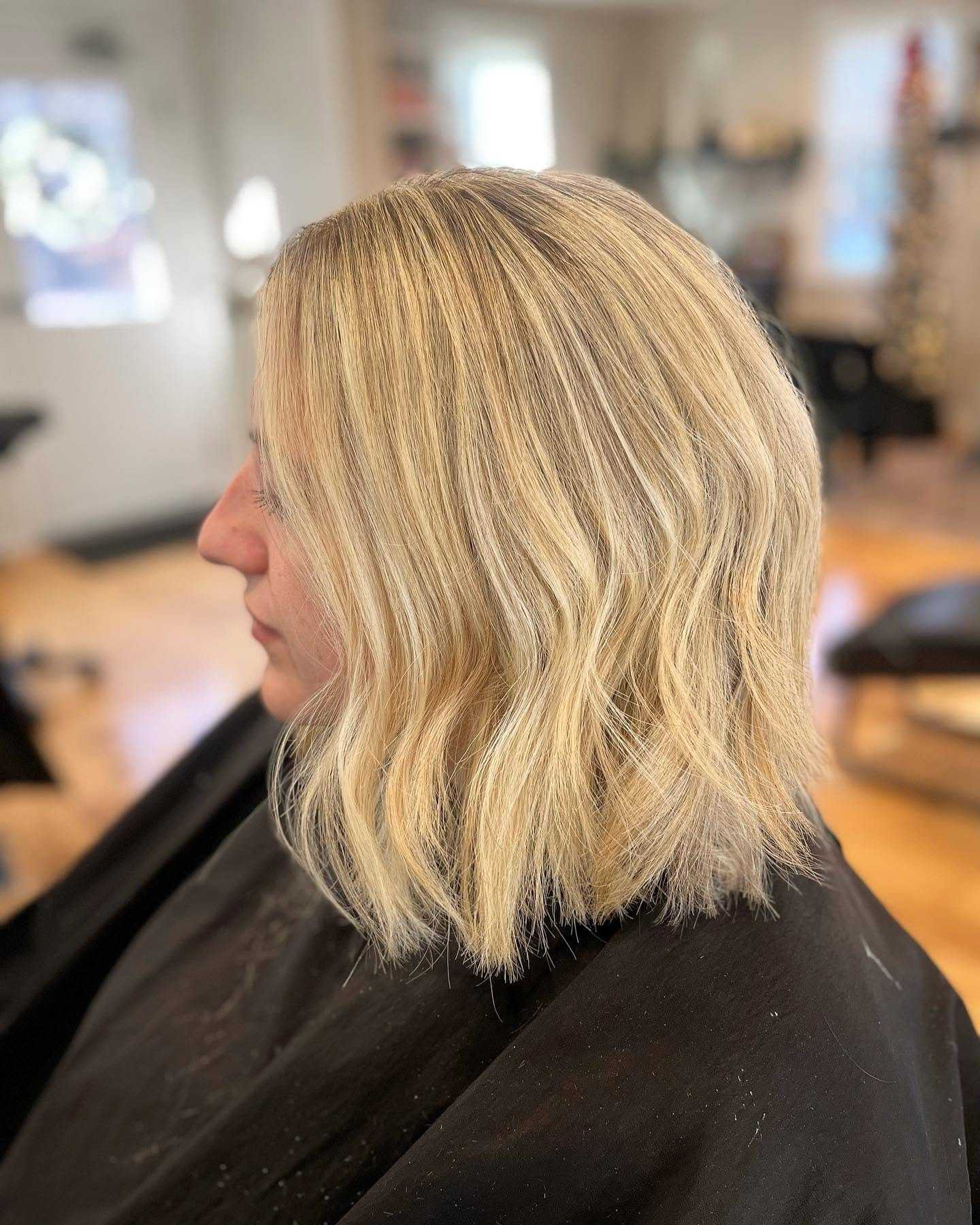 Woman with wavy blonde bob haircut sitting in a salon.