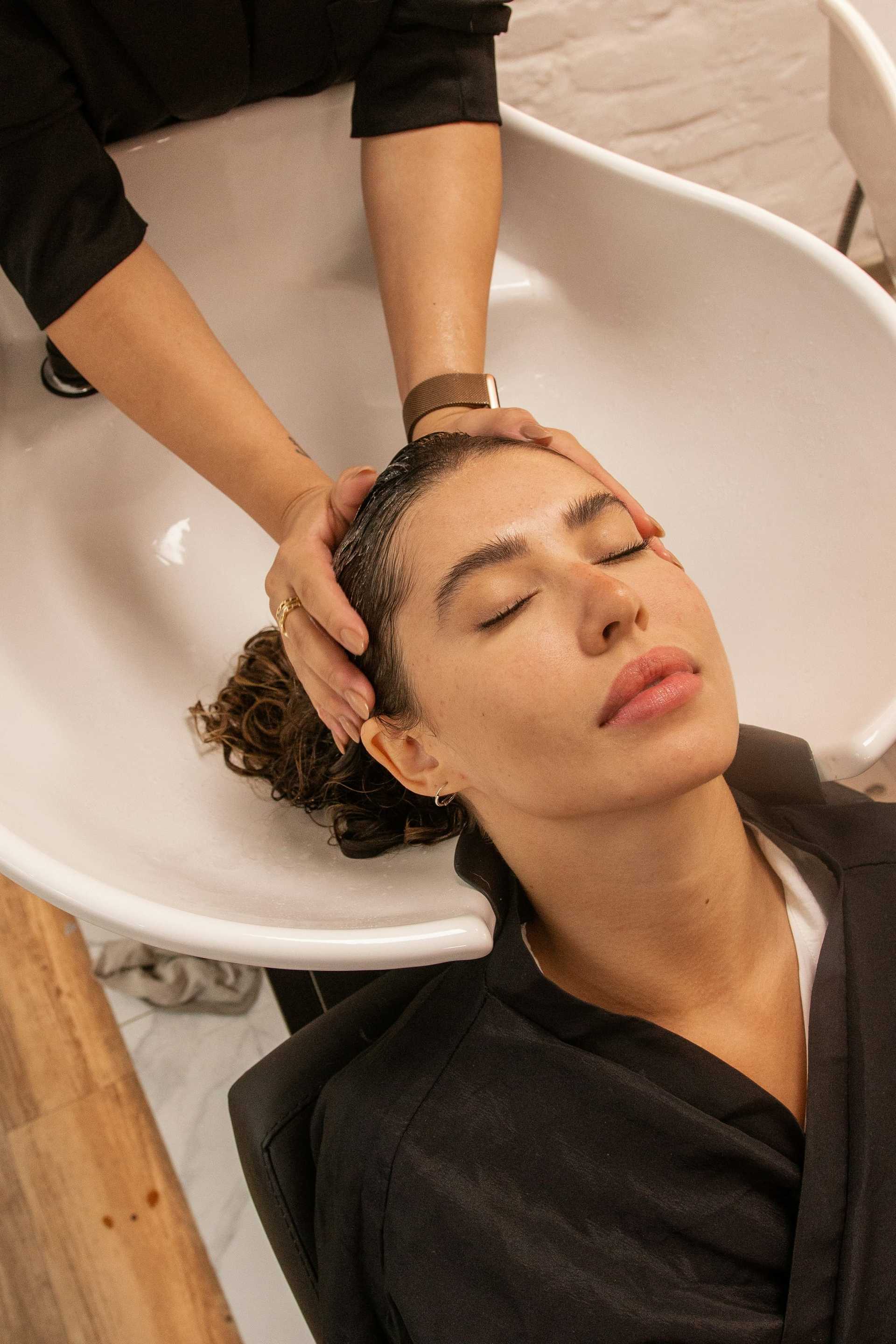 Woman enjoying a relaxing hair wash at a salon.